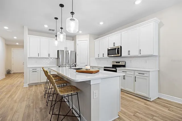 a kitchen with kitchen island granite countertop a sink a counter space stainless steel appliances and cabinets