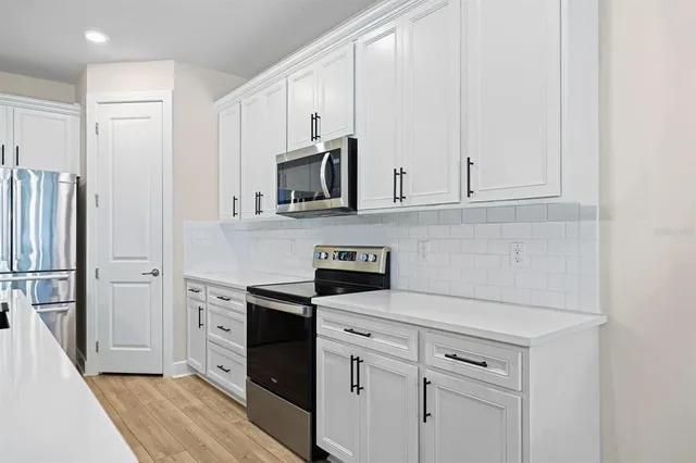 a kitchen with stainless steel appliances white cabinets and a refrigerator