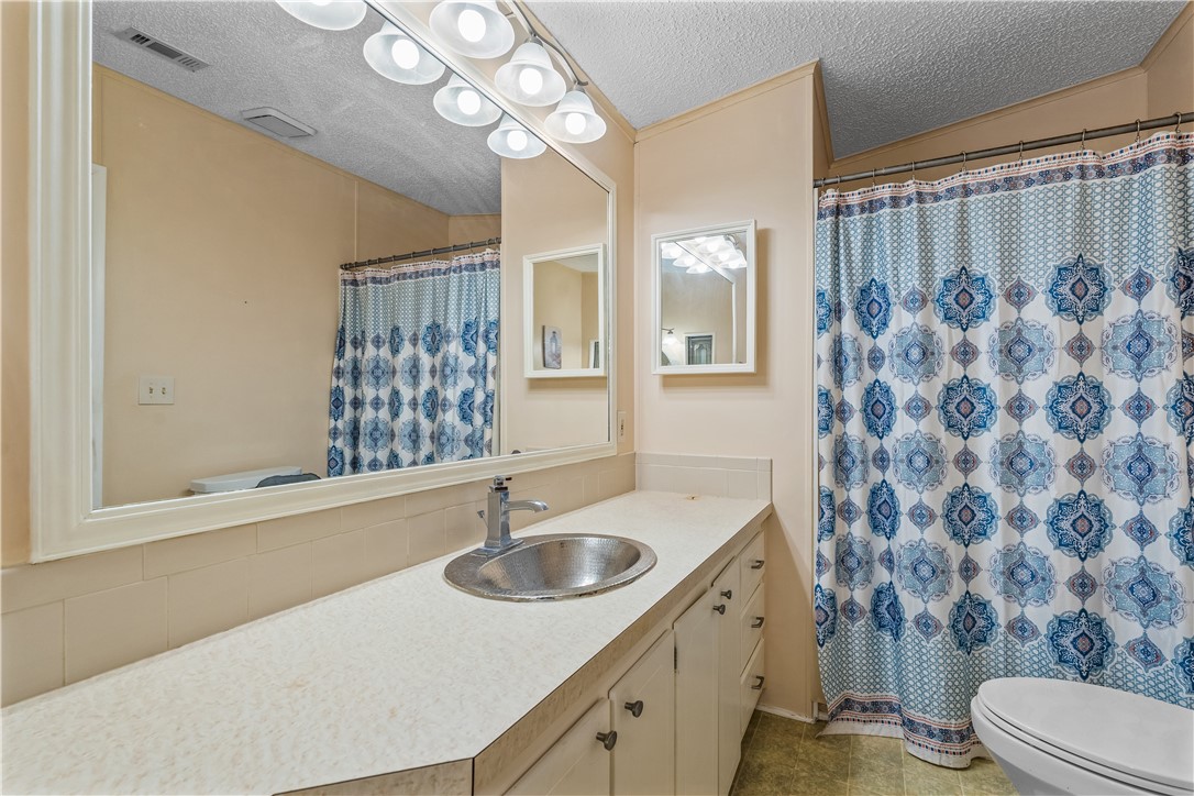 7635 Blackhawk Road Micco, FL 32976 - Photo 14 of 30 a bathroom with a sink a toilet a mirror a lamp and shower curtain