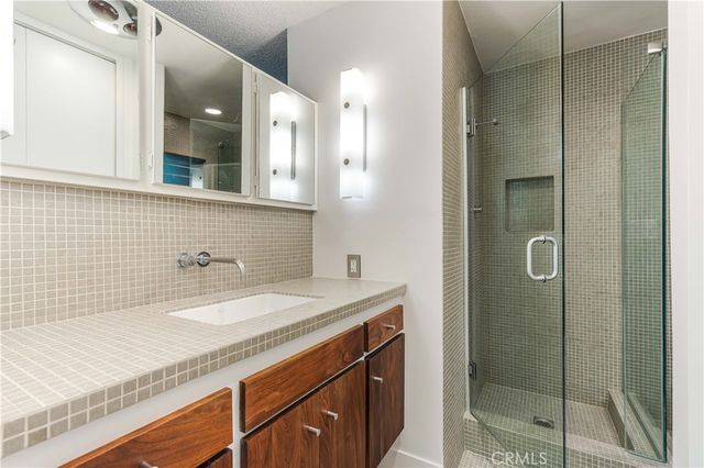 a bathroom with a granite countertop sink a mirror and shower