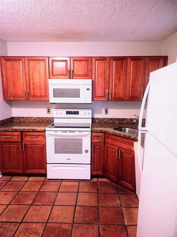 a kitchen with granite countertop a stove top oven and cabinets