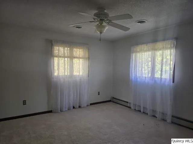 an empty room with windows and fan