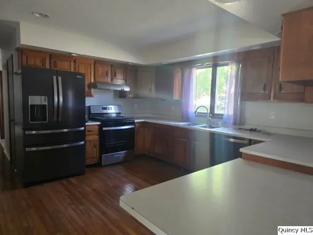 a kitchen with stainless steel appliances a refrigerator a sink a stove a counter space and cabinets