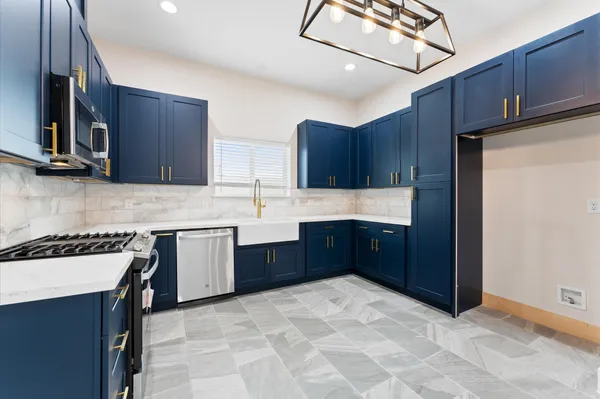 a large kitchen with stainless steel appliances granite countertop wooden cabinets a stove top oven a sink and dishwasher