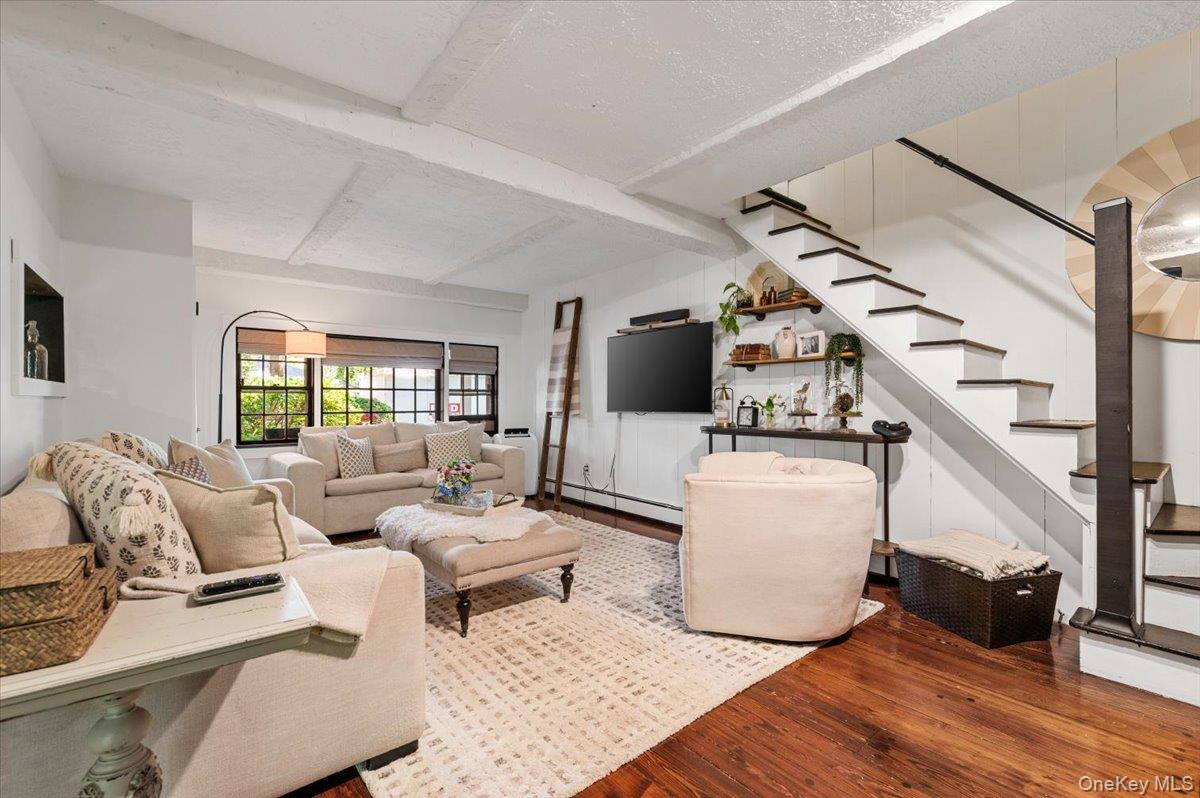 10 Rancher Place Huntington, NY 11743 - Photo 15 of 44 Living area featuring wood-finish flooring, exposed ceiling beams, and a modern staircase with dark treads and a black handrail