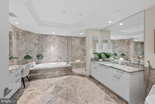 a bathroom with a granite countertop tub a sink and a large mirror