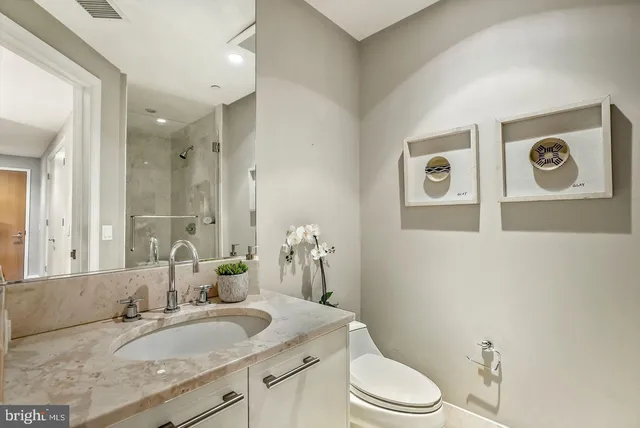 a bathroom with a granite countertop toilet sink and mirror