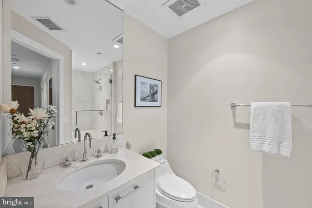 a bathroom with a toilet a sink a mirror a shower and vanity