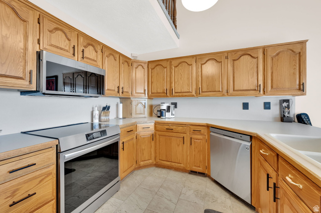 5057 South Ridgedale Drive Ogden, UT 84403 - Photo 28 of 69 Wood-finish cabinetry with black hardware, white countertops, and stainless steel appliances, including an oven/range and dishwasher