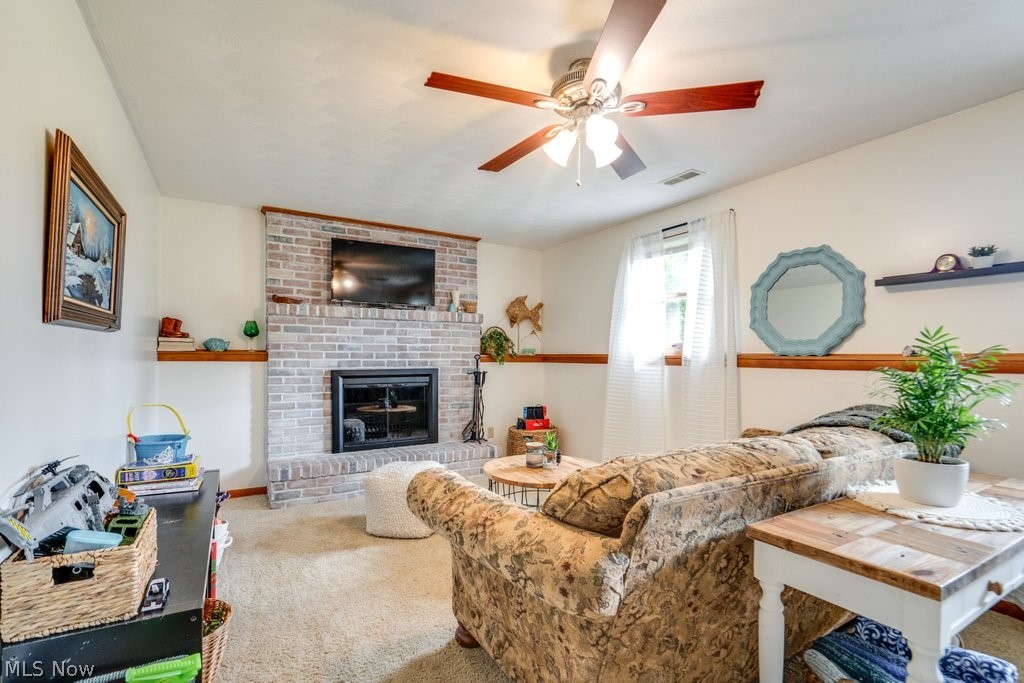 531 Porter Road Atwater, OH 44201 - Photo 33 of 44 Living room featuring brick wall, ceiling fan, carpet flooring, and a brick fireplace