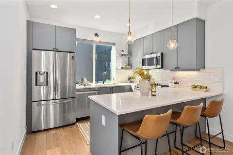 a kitchen with stainless steel appliances granite countertop a refrigerator a stove a sink dishwasher and a refrigerator with wooden floor