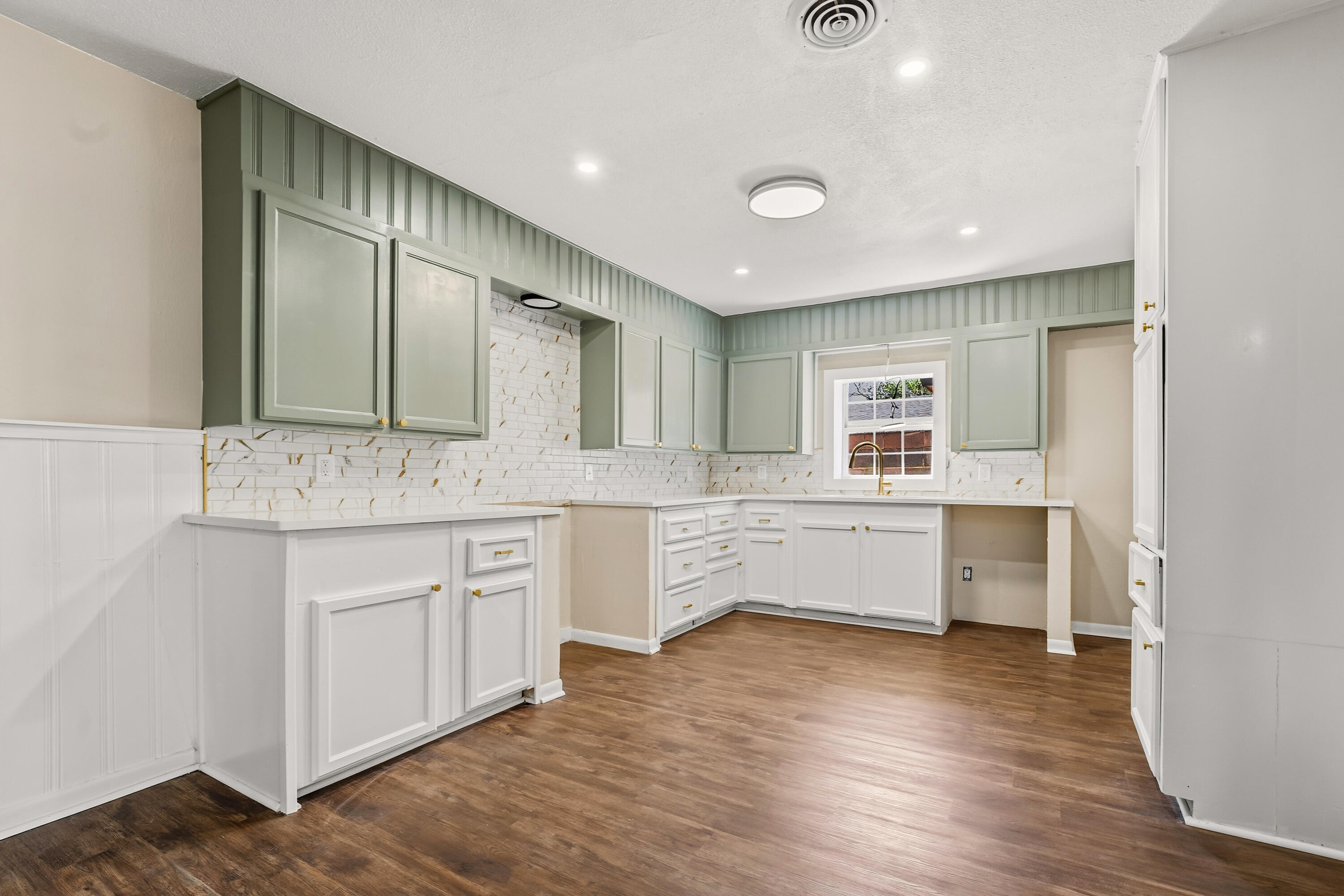 5015 16th Street Lubbock, TX 79416 - Photo 10 of 27 a large white kitchen with a sink dishwasher a stove and kitchen island with wooden floor