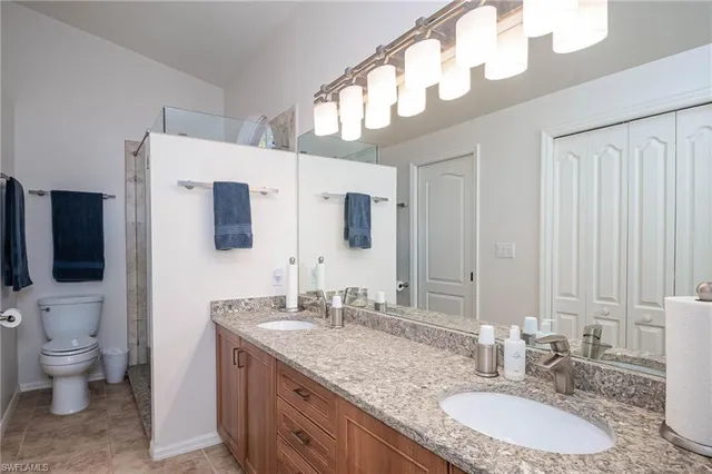 a bathroom with a granite countertop double vanity sink and a mirror