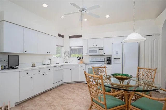 a kitchen with stainless steel appliances kitchen island granite countertop a table chairs sink and cabinets