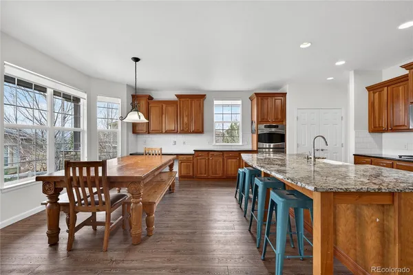 a kitchen with stainless steel appliances granite countertop a sink a stove a dining table and chairs