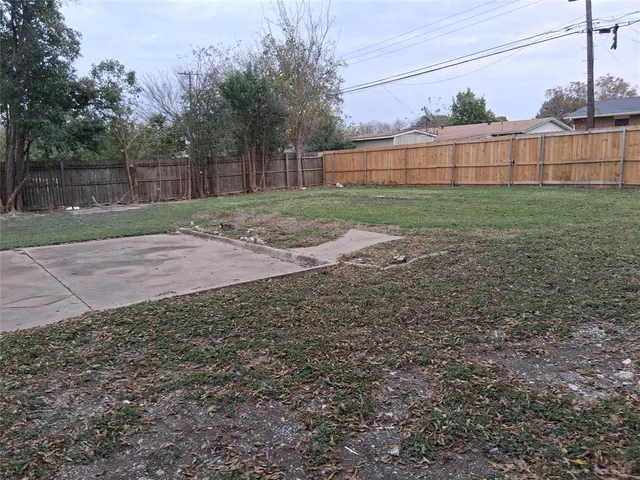 a view of a backyard with large trees and wooden fence