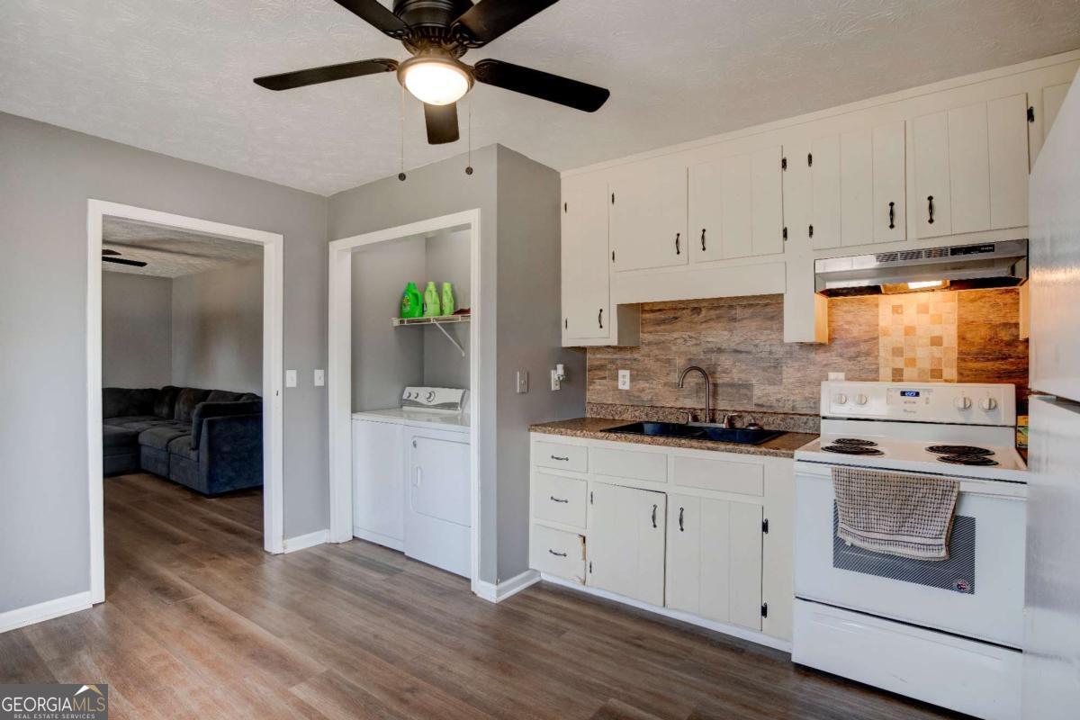 665 Caney Branch Road Lavonia, GA 30553 - Photo 17 of 26 a kitchen with granite countertop a stove a sink and white cabinets with wooden floor