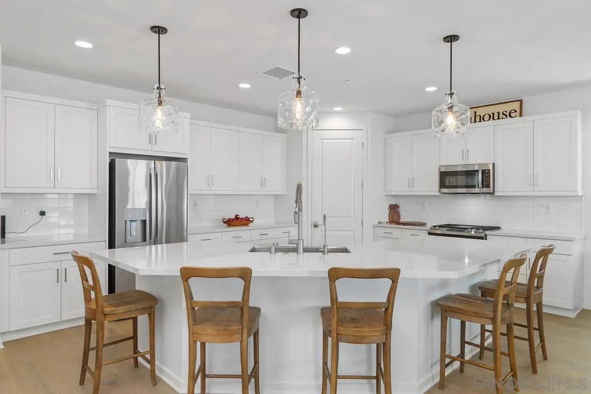 32082 Sedge Way Temecula, CA 92591 - Photo 13 of 59 a kitchen with stainless steel appliances kitchen island granite countertop a dining table chairs and white cabinets