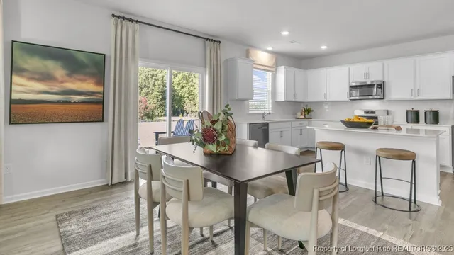 a kitchen with stainless steel appliances granite countertop a stove a refrigerator a white table and chairs with wooden floor