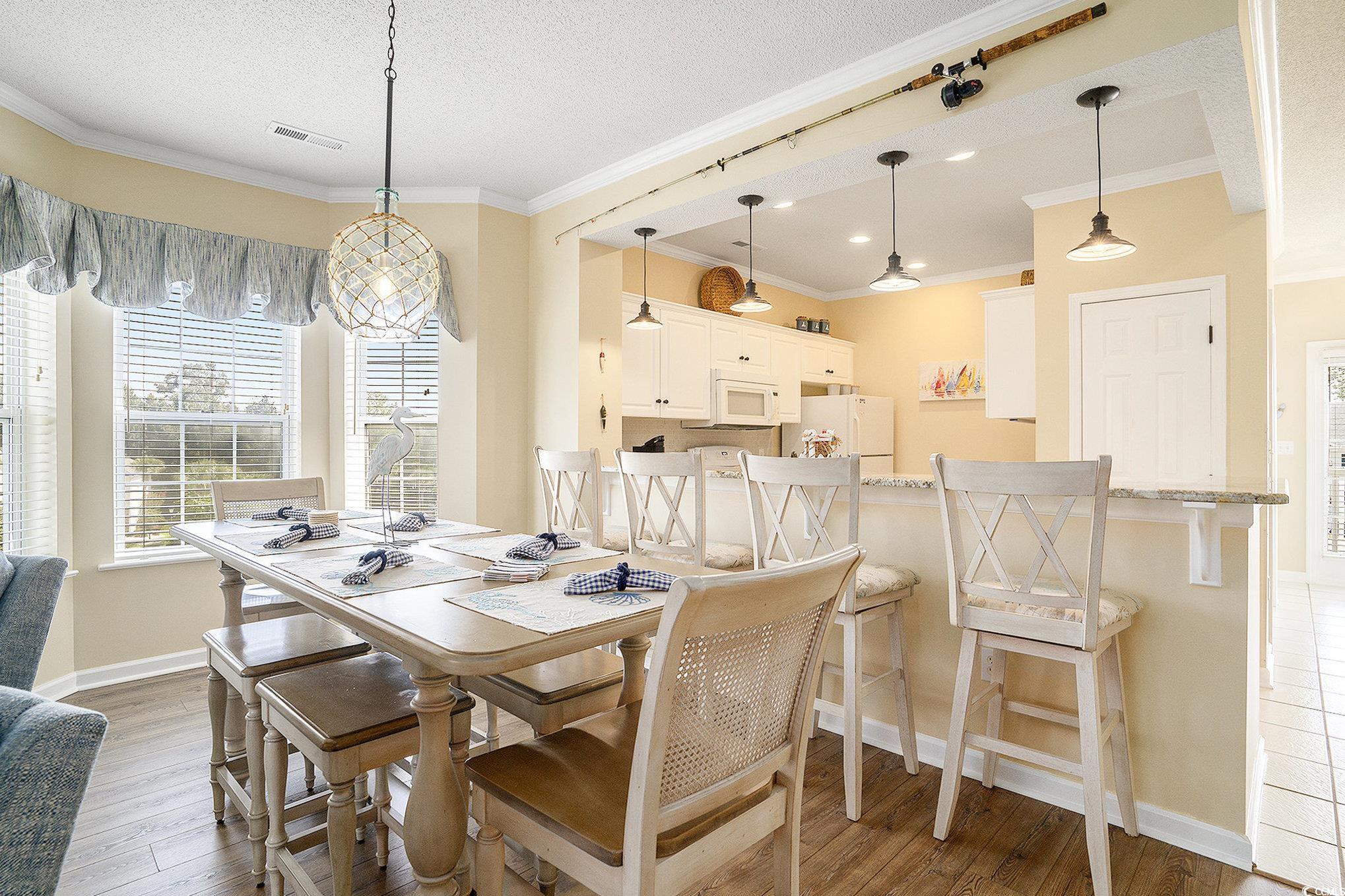 4459 Turtle Lane, Unit 3D Little River, SC 29566 - Photo 9 of 30 Dining space featuring light wood-style floors, a textured ceiling, and ornamental molding