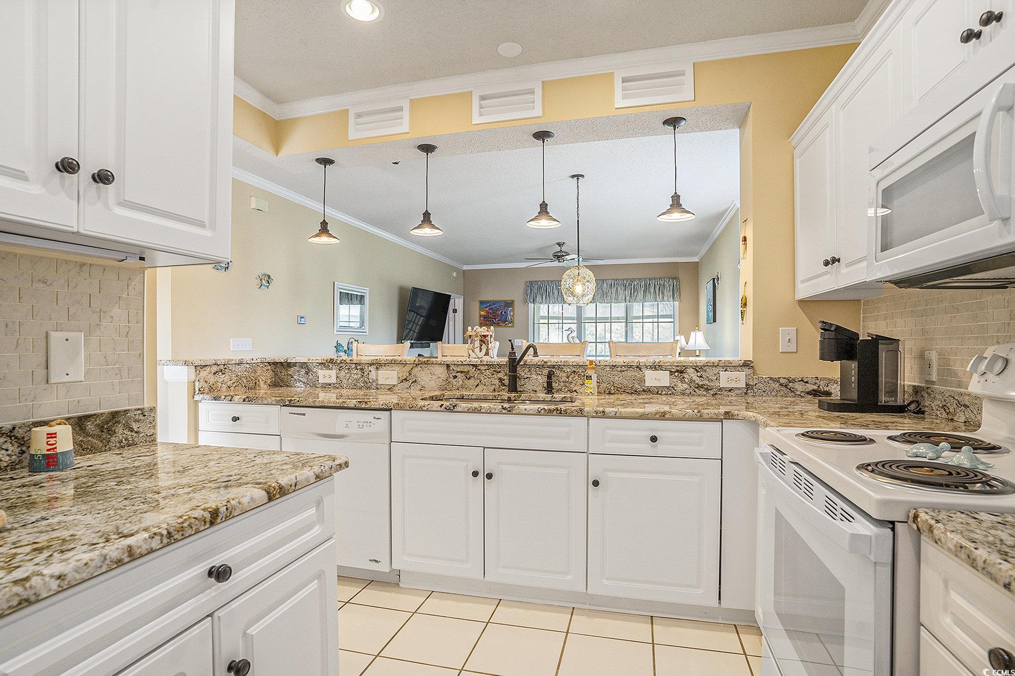 4459 Turtle Lane, Unit 3D Little River, SC 29566 - Photo 10 of 30 Kitchen featuring backsplash, white appliances, white cabinetry, light stone counters, and light tile patterned floors