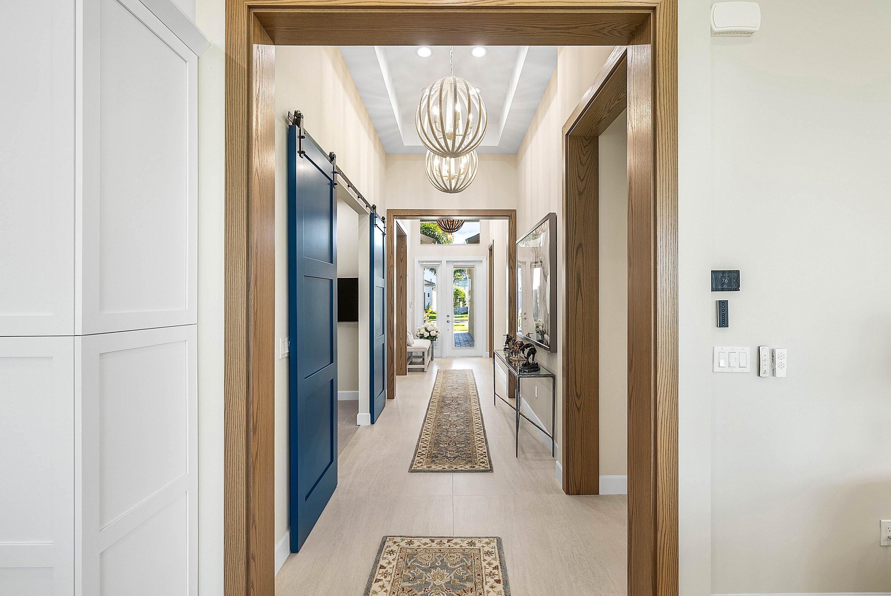 12626 Parrot Pond Road Boynton Beach, FL 33473 - Photo 15 of 67 a hallway with wooden floor and a chandelier