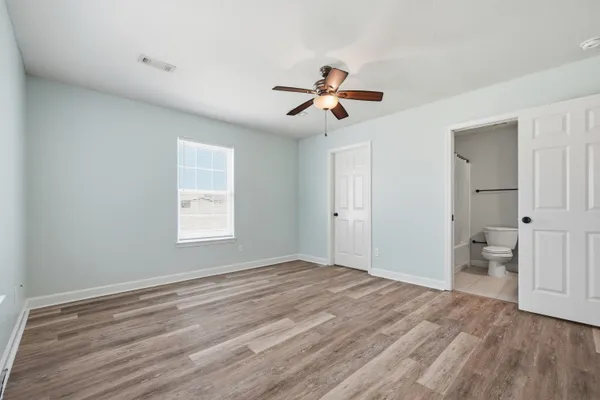 a view of empty room with wooden floor and ceiling fan