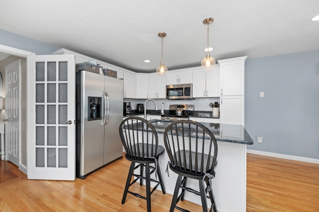 10 Shade Street Waltham, MA 02452 - Photo 21 of 33 a kitchen with stainless steel appliances granite countertop a stove a refrigerator a kitchen island a rug a stove and a wooden floors