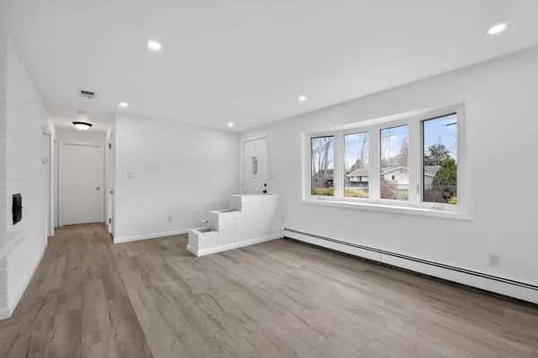a view of an empty room with a window and wooden floor