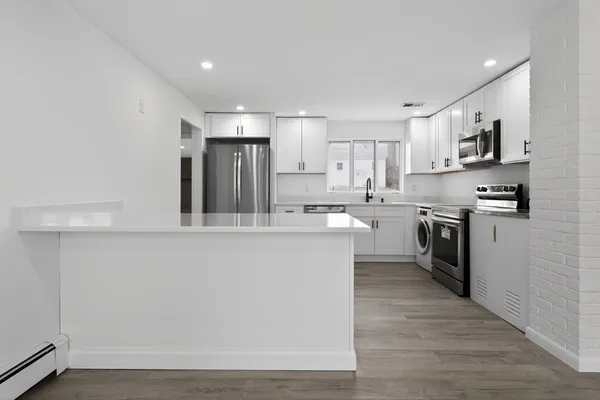 a kitchen with stainless steel appliances a sink a stove a refrigerator cabinets and a window