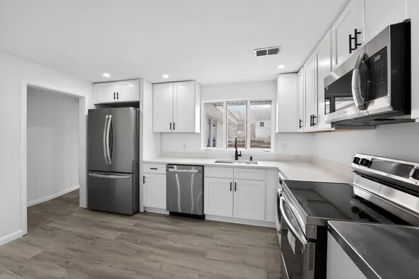 a kitchen with stainless steel appliances a sink a stove a microwave and cabinets