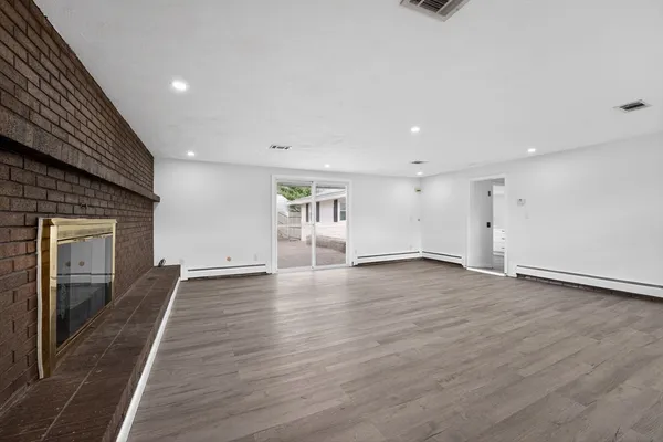 an empty room with wooden floor and fireplace