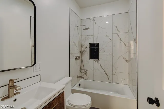 a bathroom with a bathtub shower sink vanity and toilet