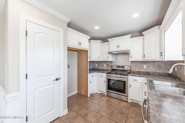 a kitchen with stainless steel appliances granite countertop a stove sink and cabinets