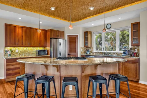 a kitchen with stainless steel appliances granite countertop a kitchen island and chairs in it