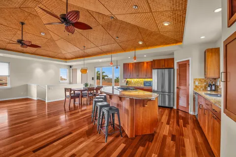 a kitchen with stainless steel appliances a dining table chairs stove refrigerator and cabinets