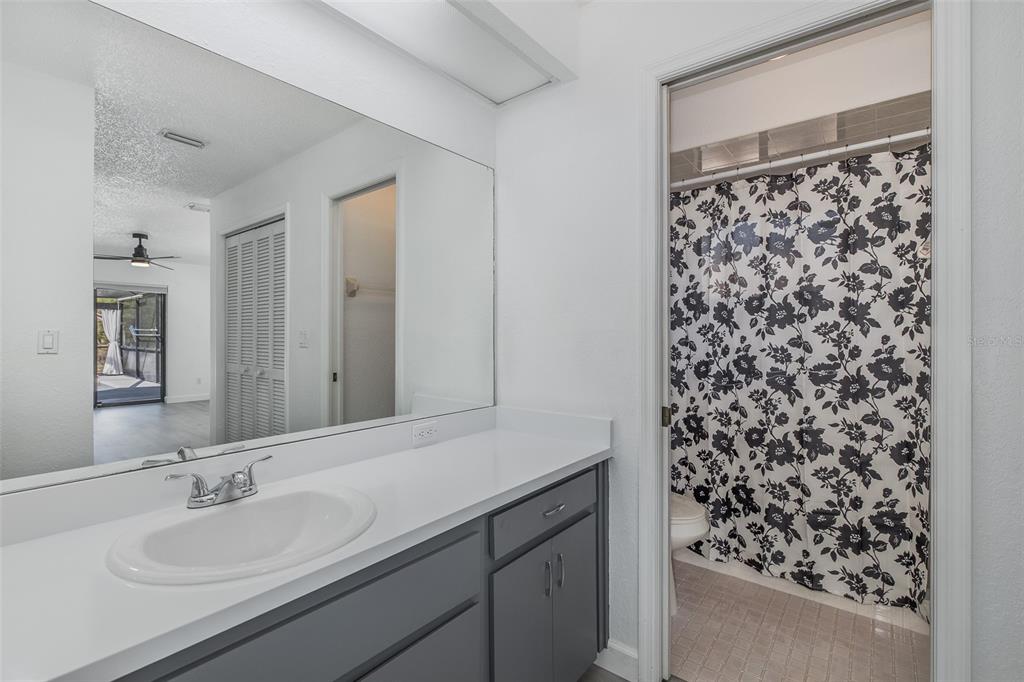8285 Galgano Lane Spring Hill, FL 34606 - Photo 25 of 55 a bathroom with a granite countertop sink a mirror a vanity and a shower