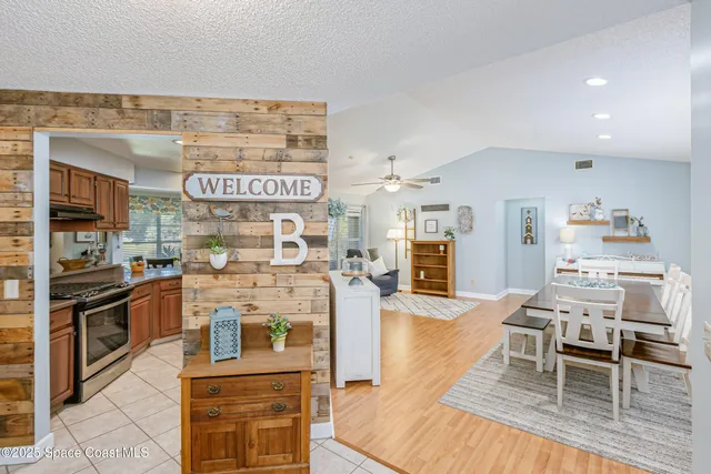 a kitchen with stainless steel appliances kitchen island granite countertop a refrigerator a stove top oven and a dining table with wooden floor