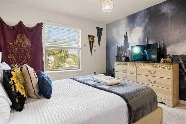 a bedroom with a bed and a flat tv screen on dresser