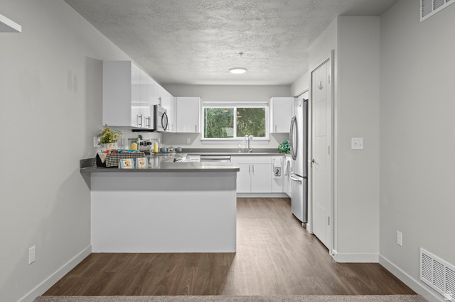 64 West 600 South, Unit C205 Springville, UT 84663 - Photo 2 of 28 Kitchen featuring white cabinets, a peninsula, stainless steel appliances, wood finished floors, and a textured ceiling