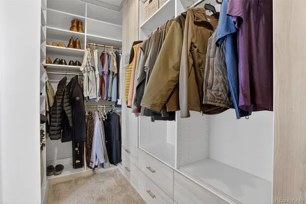 a view of walk in closet with clothes and shoes