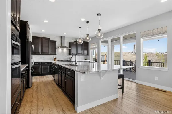 a large kitchen with stainless steel appliances granite countertop a stove and a wooden floors