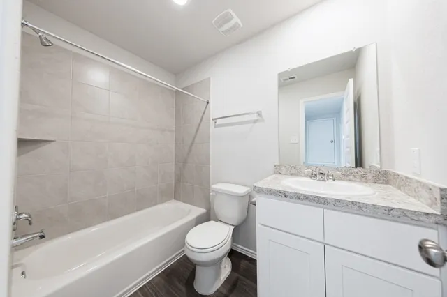 a bathroom with a granite countertop sink toilet vanity mirror bathtub and shower