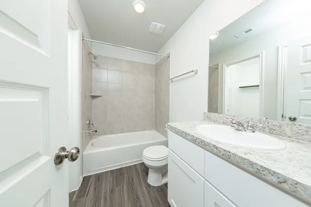 a bathroom with a granite countertop sink a toilet and shower