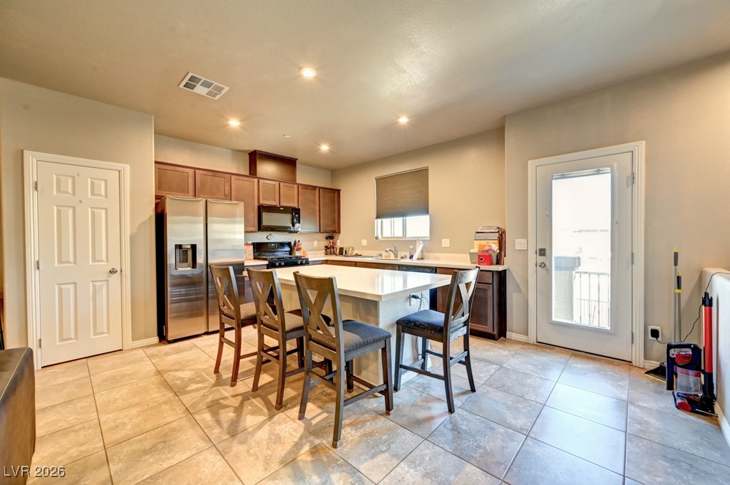 1284 Arcadia Rim Place Henderson, NV 89002 - Photo 8 of 27 Kitchen with black appliances, a center island, a kitchen breakfast bar, recessed lighting, and wood finish cabinets