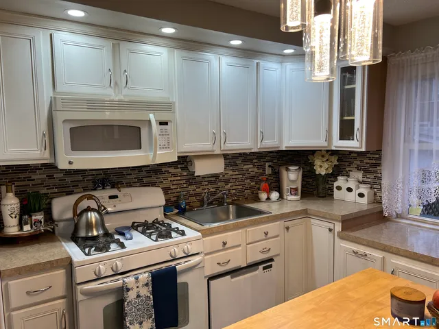 a kitchen with stainless steel appliances granite countertop a stove a sink and a microwave