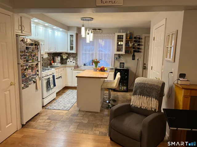 a living room with furniture a kitchen view and a refrigerator
