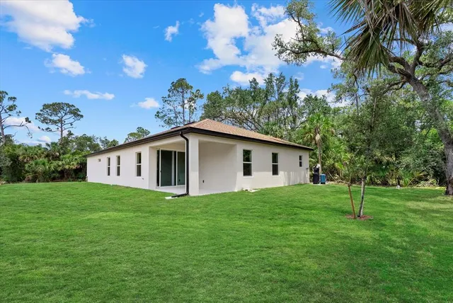 a white house with a big yard and a large tree