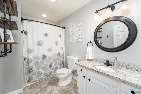 a bathroom with a granite countertop toilet sink and mirror