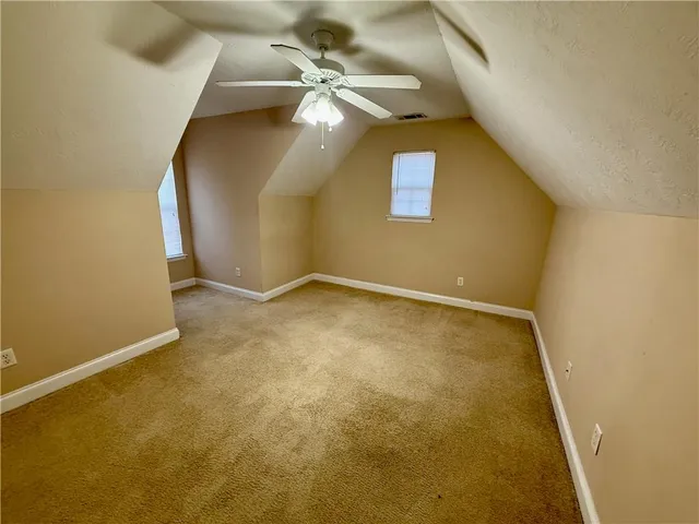 an empty room with a chandelier fan and entryway